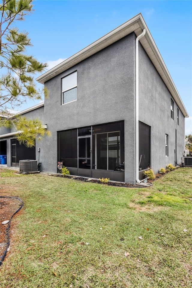 rear view of property with a yard, a sunroom, and central air condition unit