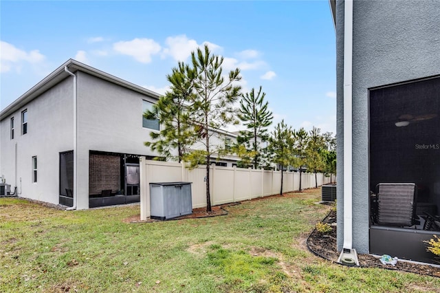 view of yard featuring a sunroom and central AC