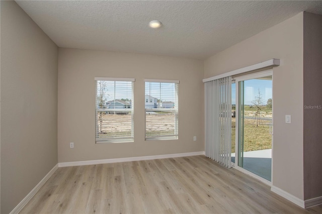 empty room with light hardwood / wood-style floors and a textured ceiling