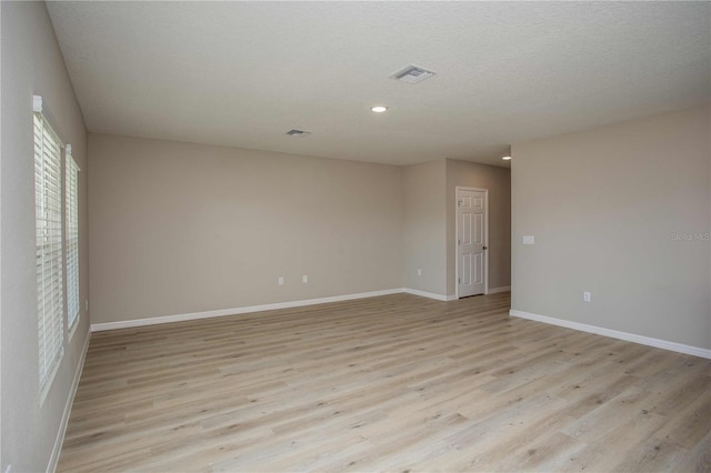 unfurnished room with light hardwood / wood-style flooring and a textured ceiling