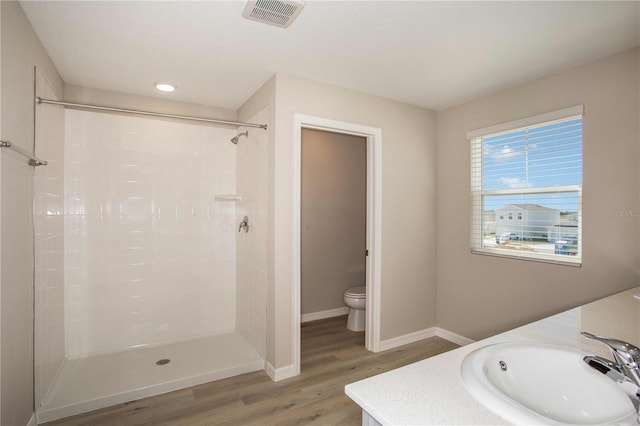 bathroom featuring walk in shower, hardwood / wood-style floors, vanity, and toilet