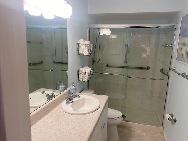 bathroom featuring tile patterned floors, vanity, toilet, and a shower with door