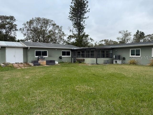 rear view of property with a sunroom, central AC unit, and a lawn