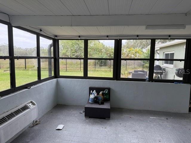 unfurnished sunroom featuring an AC wall unit