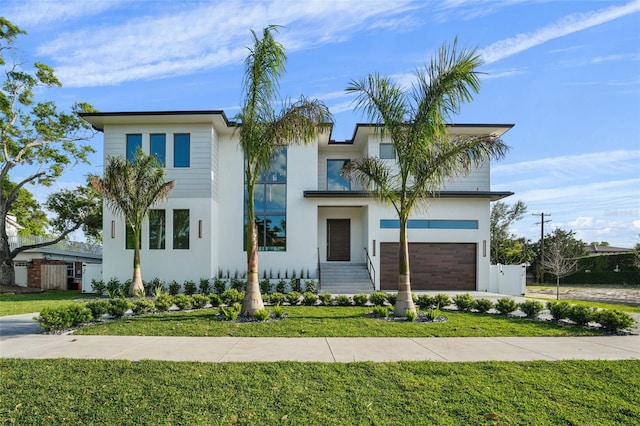 contemporary house with stucco siding, fence, an attached garage, driveway, and a front yard