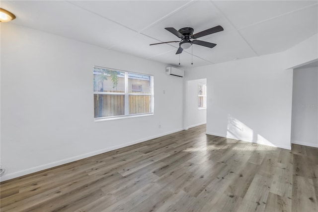 unfurnished room with ceiling fan, light hardwood / wood-style flooring, and an AC wall unit