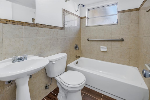 bathroom with toilet, tile walls, and tiled shower / bath