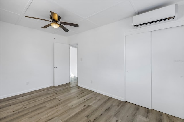 unfurnished bedroom featuring light wood-type flooring, a wall mounted AC, ceiling fan, and a closet