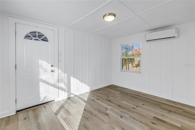 spare room with a wall mounted AC and light wood-type flooring