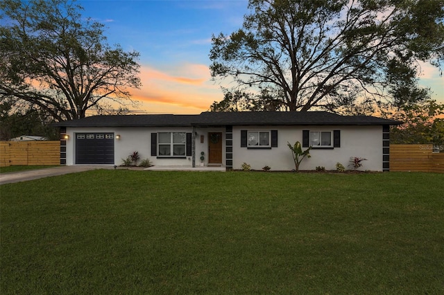 ranch-style home with a garage and a lawn