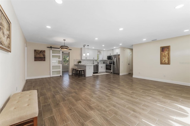 unfurnished living room featuring a barn door and light hardwood / wood-style flooring