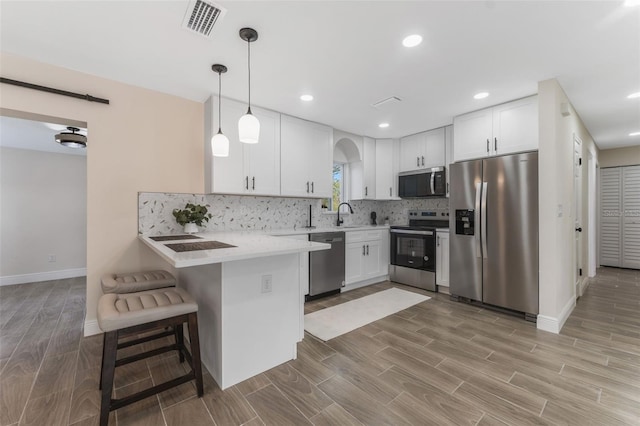 kitchen with a kitchen bar, kitchen peninsula, white cabinets, and appliances with stainless steel finishes