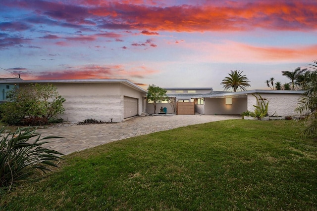 view of front of property with stucco siding, decorative driveway, an attached garage, and a front lawn