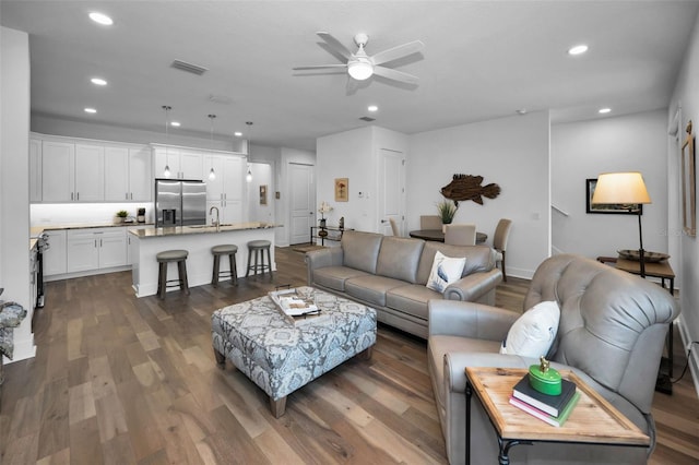 living room featuring ceiling fan, sink, and dark hardwood / wood-style flooring