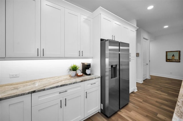 kitchen with stainless steel refrigerator with ice dispenser, light stone counters, white cabinets, and dark hardwood / wood-style flooring