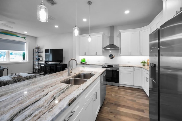 kitchen with stainless steel appliances, wall chimney exhaust hood, white cabinets, and sink