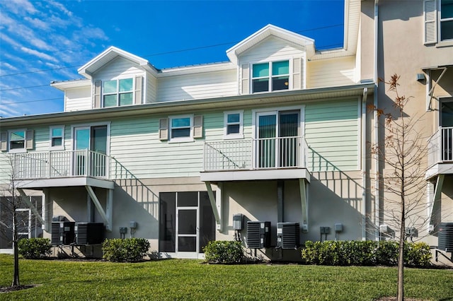 rear view of property with central air condition unit and a yard