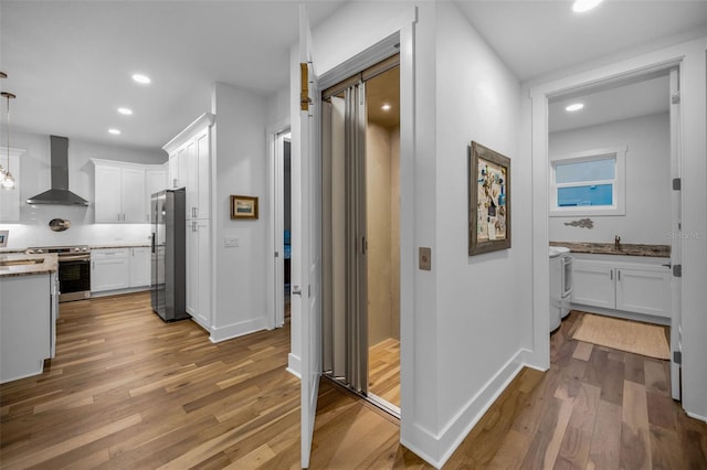 corridor with sink, washer / dryer, and light hardwood / wood-style floors