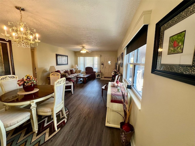 dining room featuring ceiling fan with notable chandelier, a textured ceiling, and dark hardwood / wood-style floors