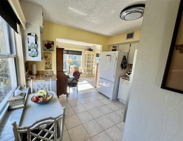 kitchen featuring light tile patterned floors, white appliances, and a textured ceiling