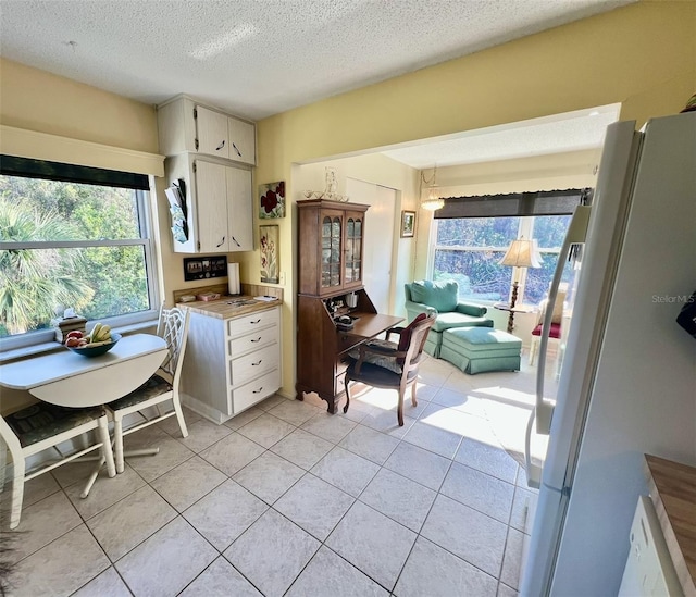 kitchen with a textured ceiling, light tile patterned floors, and white fridge