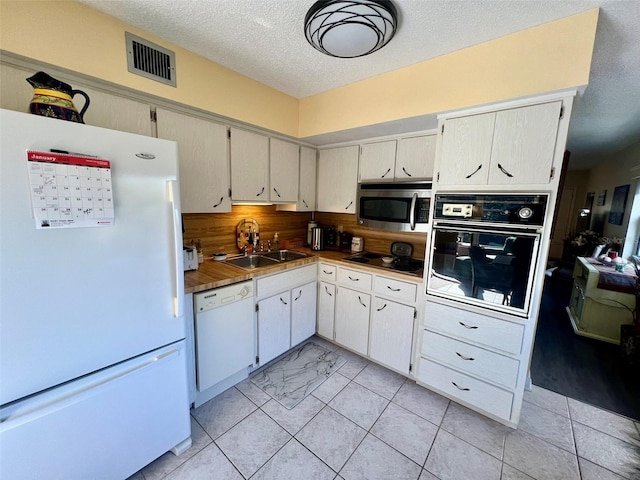 kitchen featuring black appliances, decorative backsplash, sink, white cabinetry, and a textured ceiling