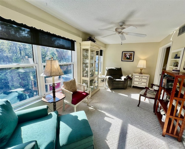 carpeted living room with a textured ceiling and ceiling fan