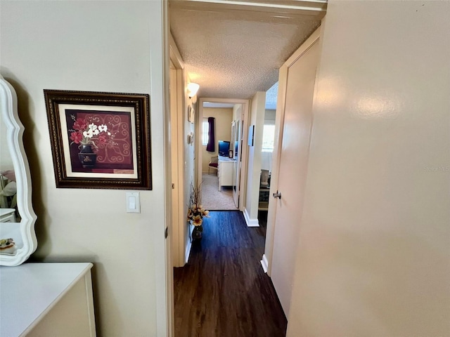 hallway with a textured ceiling and dark hardwood / wood-style flooring