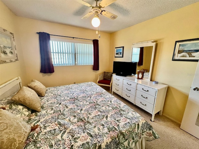 bedroom featuring ceiling fan, light colored carpet, and a textured ceiling