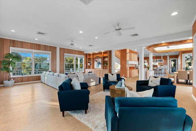 interior space featuring ceiling fan, crown molding, light wood-type flooring, and wood walls