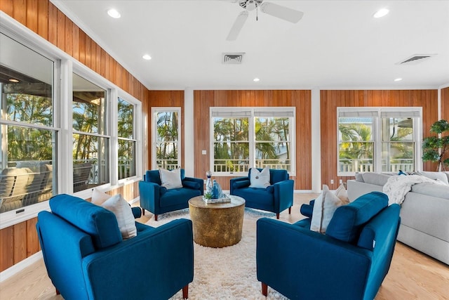 living room with recessed lighting, visible vents, wood walls, and crown molding