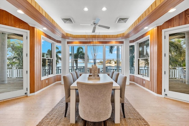 sunroom with ceiling fan and a water view