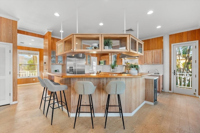 kitchen featuring ornamental molding, appliances with stainless steel finishes, light hardwood / wood-style floors, and a wealth of natural light