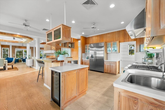 kitchen featuring ceiling fan, a kitchen bar, built in fridge, and exhaust hood