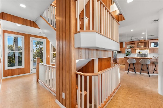 hallway featuring wooden walls and light hardwood / wood-style floors