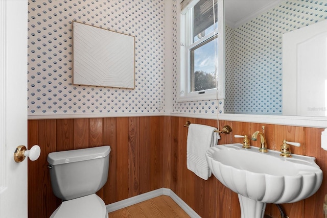 bathroom featuring toilet, sink, wood walls, ornamental molding, and hardwood / wood-style flooring