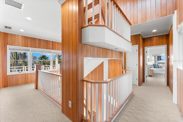 hallway featuring light carpet and wood walls