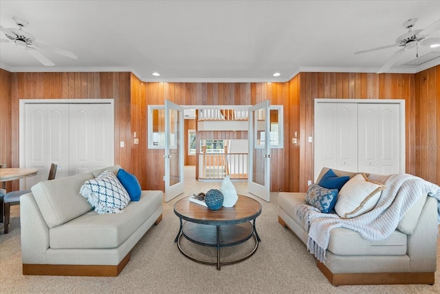 living room with french doors, ceiling fan, crown molding, and wood walls