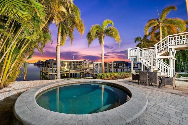 pool at dusk with a water view and a boat dock