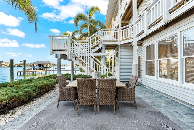 view of patio / terrace with outdoor dining space, stairs, and a water view