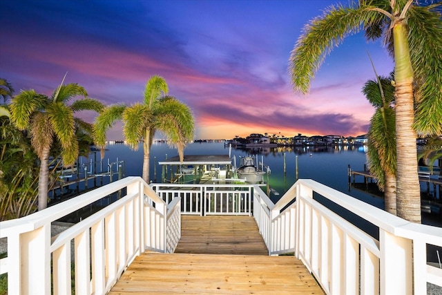 deck at dusk with a water view and a dock