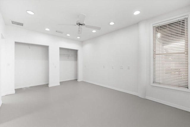 unfurnished bedroom featuring multiple closets, concrete floors, and ceiling fan