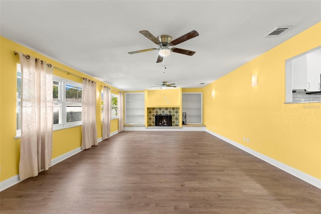 unfurnished living room with wood-type flooring, built in shelves, and ceiling fan