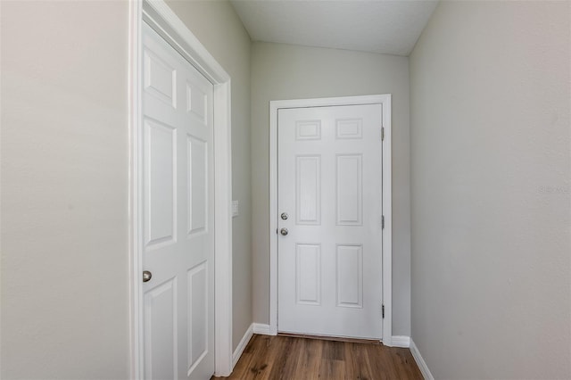 doorway featuring baseboards and dark wood-type flooring