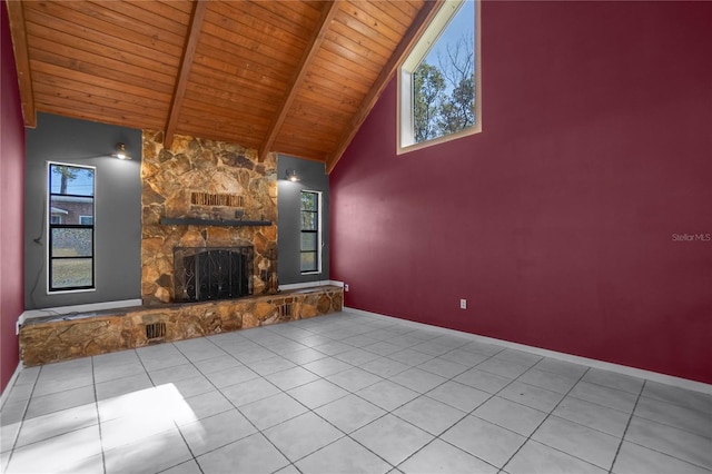 unfurnished living room with beamed ceiling, light tile patterned floors, high vaulted ceiling, wood ceiling, and a stone fireplace