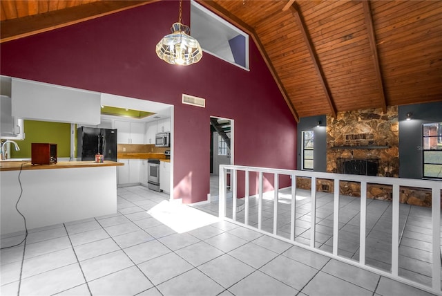 interior space featuring a stone fireplace, light tile patterned floors, high vaulted ceiling, wooden ceiling, and sink