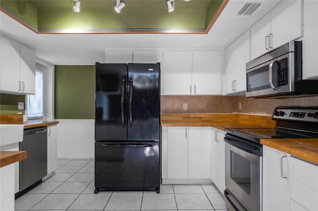 kitchen with white cabinets, light tile patterned flooring, backsplash, and appliances with stainless steel finishes