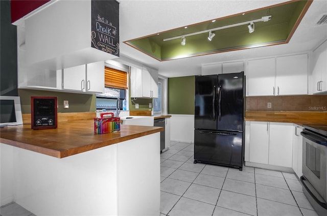 kitchen with butcher block counters, white cabinetry, a tray ceiling, and appliances with stainless steel finishes