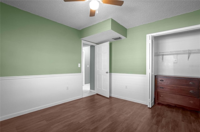 unfurnished bedroom featuring dark hardwood / wood-style flooring, a closet, ceiling fan, and a textured ceiling