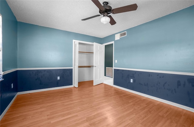 unfurnished bedroom featuring hardwood / wood-style floors, a closet, ceiling fan, and a textured ceiling